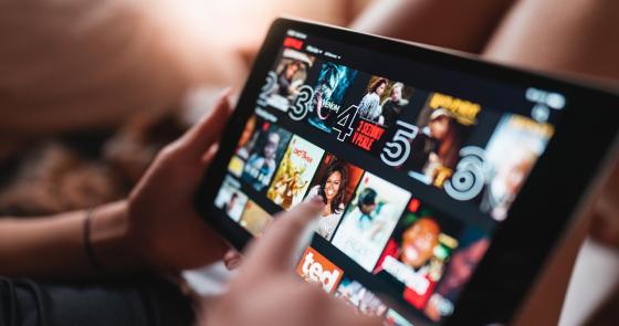 Mano sfiora schermo tablet, esplorando emozioni visive di film e serie.