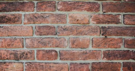Muro di mattoni rossi, ruvido e antico, evoca storie di tempi passati.