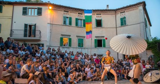 Spettacolo di strada, artisti giocolano davanti a una folla entusiasta.