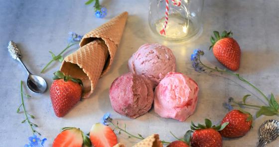Gelato e fragole su tavolo con fiori blu, atmosfera dolce e invitante.