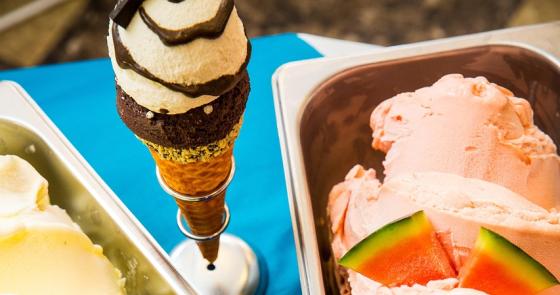 Gelati colorati e cremosi con frutta fresca su un tavolo blu.