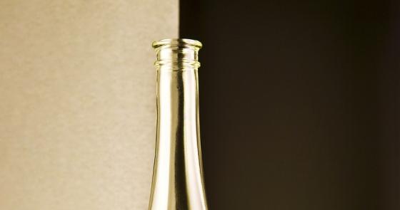 Bottiglia e calice di vino bianco accanto a una conchiglia su sfondo elegante.