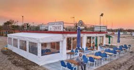 Ristorante sulla spiaggia al tramonto, atmosfera serena e accogliente.
