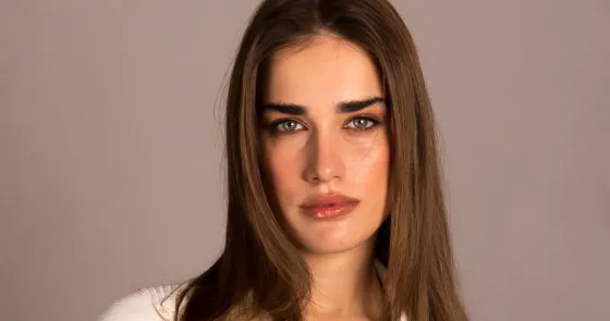 Ritratto femminile intenso, sguardo profondo e capelli castani lisci.