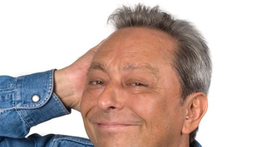 Uomo sorridente in camicia di jeans, esprime simpatia e serenità.