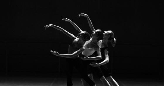Tre ballerini in armonia, movimenti eleganti e luce soffusa.