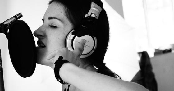 Cantante appassionata in studio, cuffie e microfono, emozione intensa.