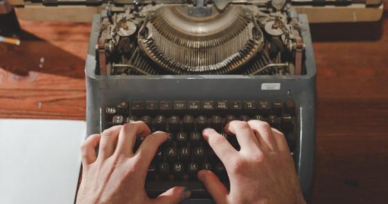 Mani su una macchina da scrivere evocano nostalgia e creatività.
