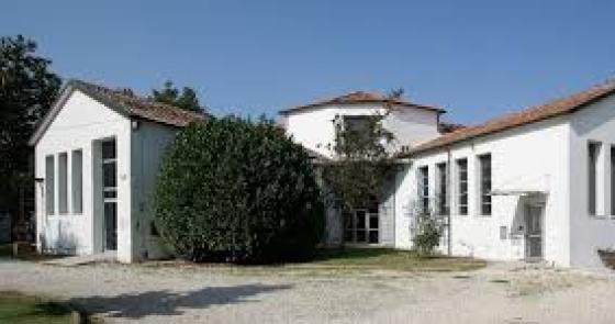Edificio bianco, tranquillo, immerso nella natura, con tetti rossi e ampie finestre.