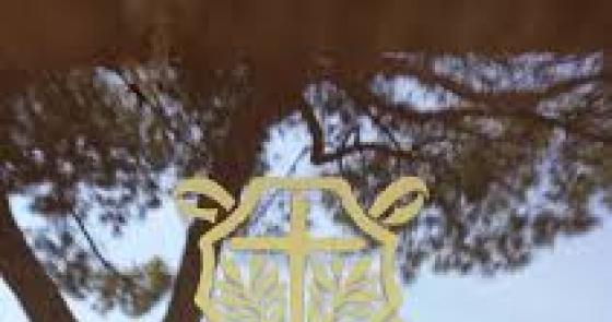 Logo dorato del museo, alberi e cielo azzurro evocano tranquillità.