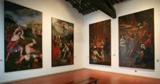 Sala d'arte con grandi dipinti emozionanti su pareti bianche e pavimento in cotto.