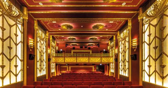 Teatro lussuoso con velluti rossi e decorazioni dorate, atmosfera elegante e affascinante.