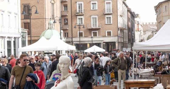 Folla vivace al mercato all'aperto, libri e bancarelle colorate.