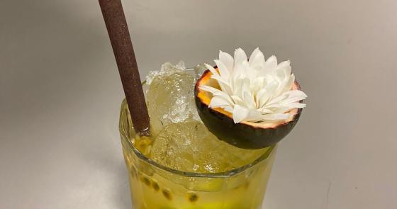 Cocktail tropicale con ghiaccio, frutto della passione e fiore bianco.
